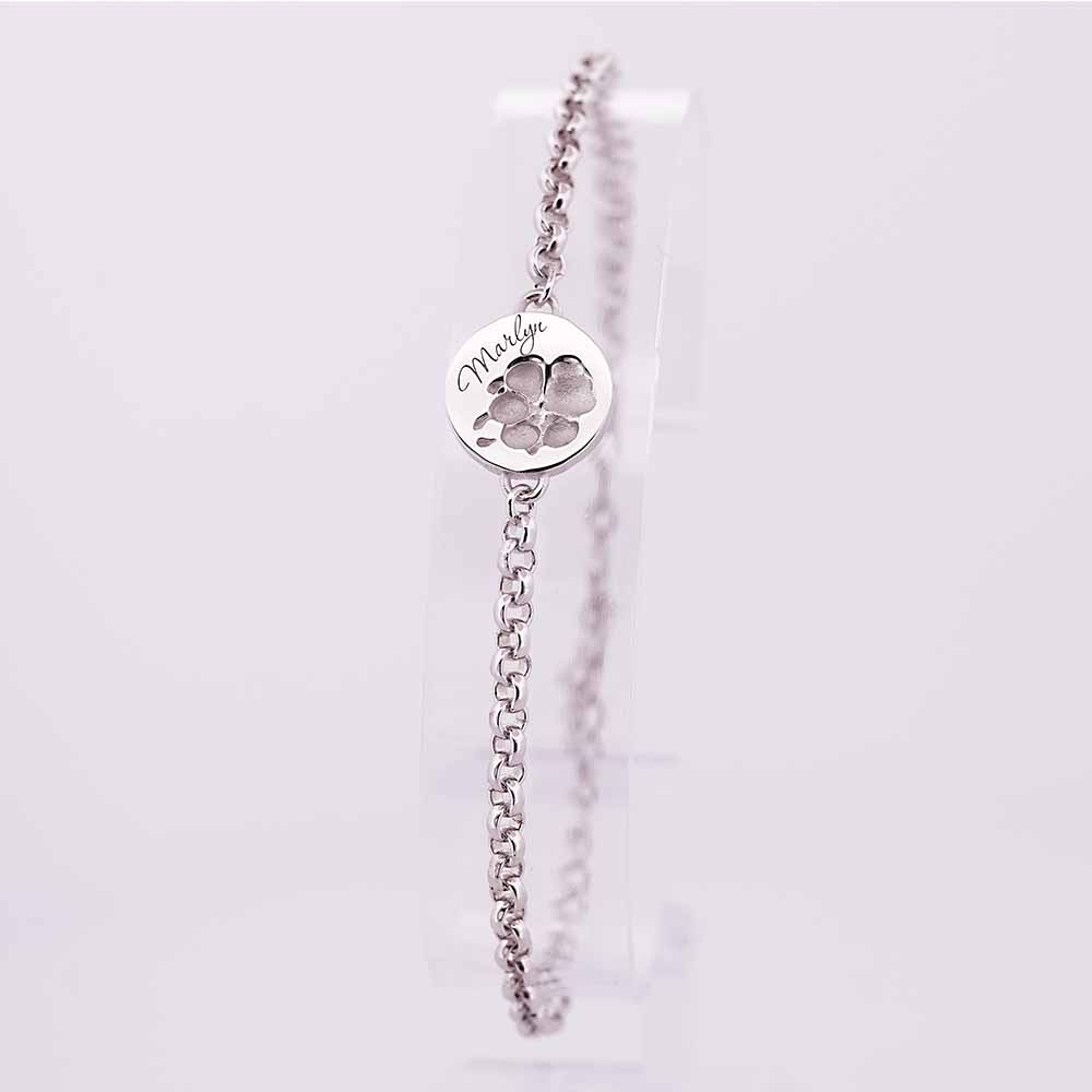 Silbernes Armband mit rundem Anhänger, eingravierter Pfotenform und Gravur Marlyn, auf hellem Hintergrund